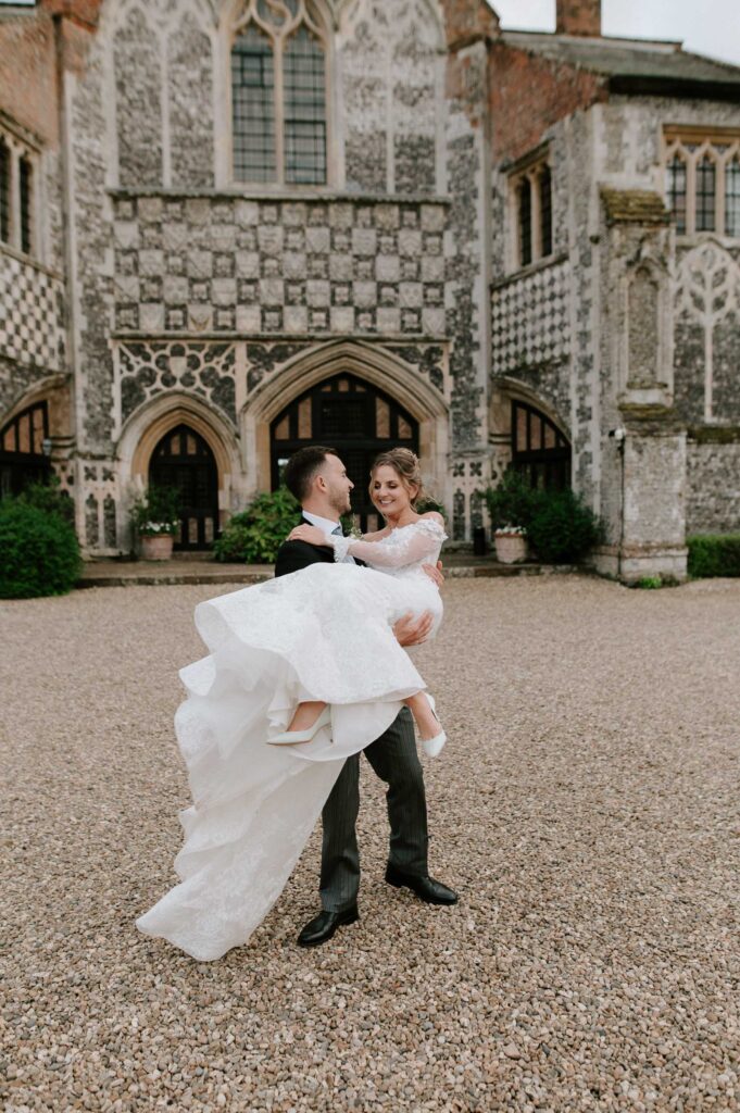 Bride and groom spinning together outside Butley Priory during relaxed portraits.

