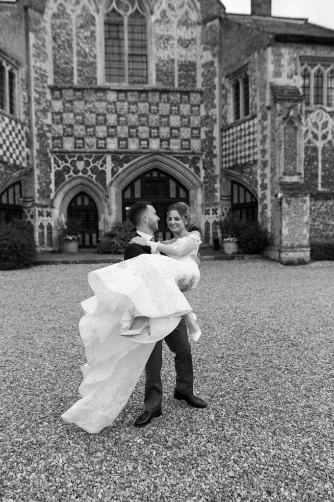 Bride and groom spinning together outside Butley Priory during relaxed portraits.
