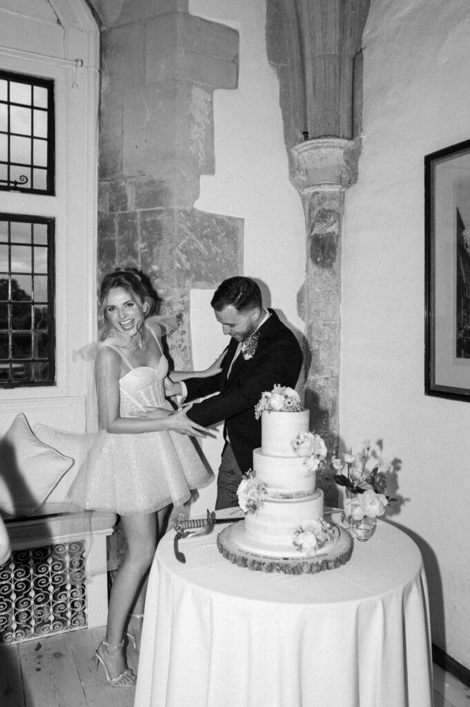 Bride and groom cutting their wedding cake during evening celebrations.