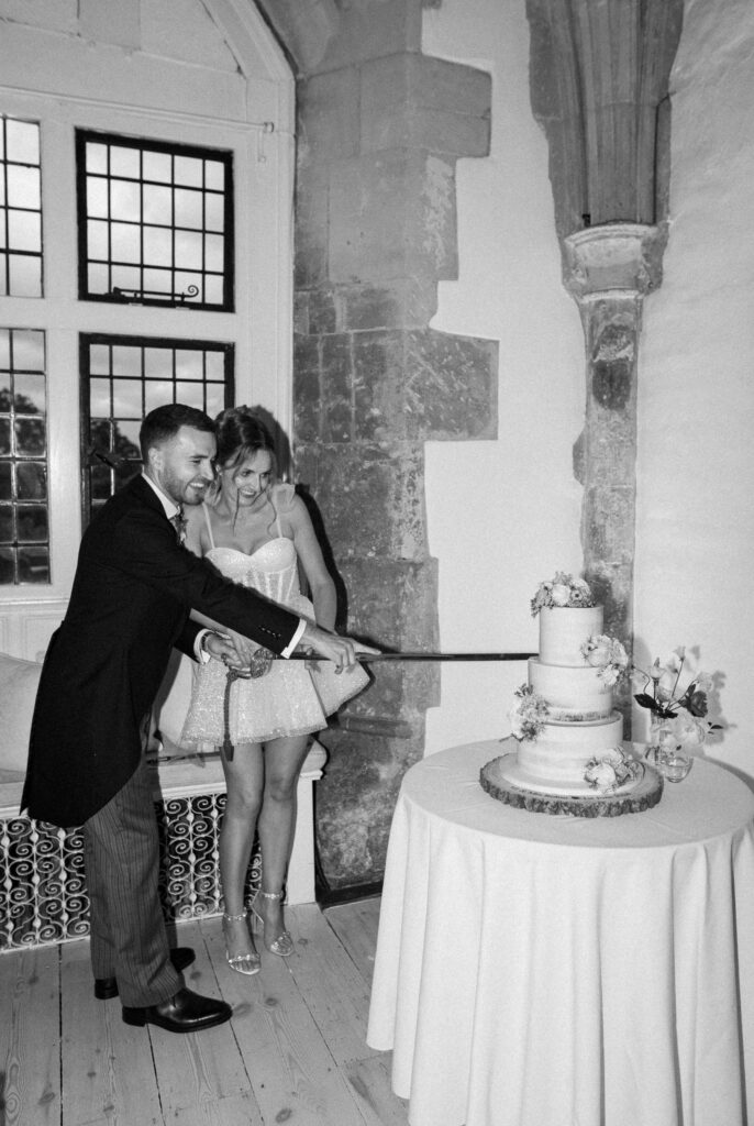 Bride and groom cutting their wedding cake with a sword during the reception.