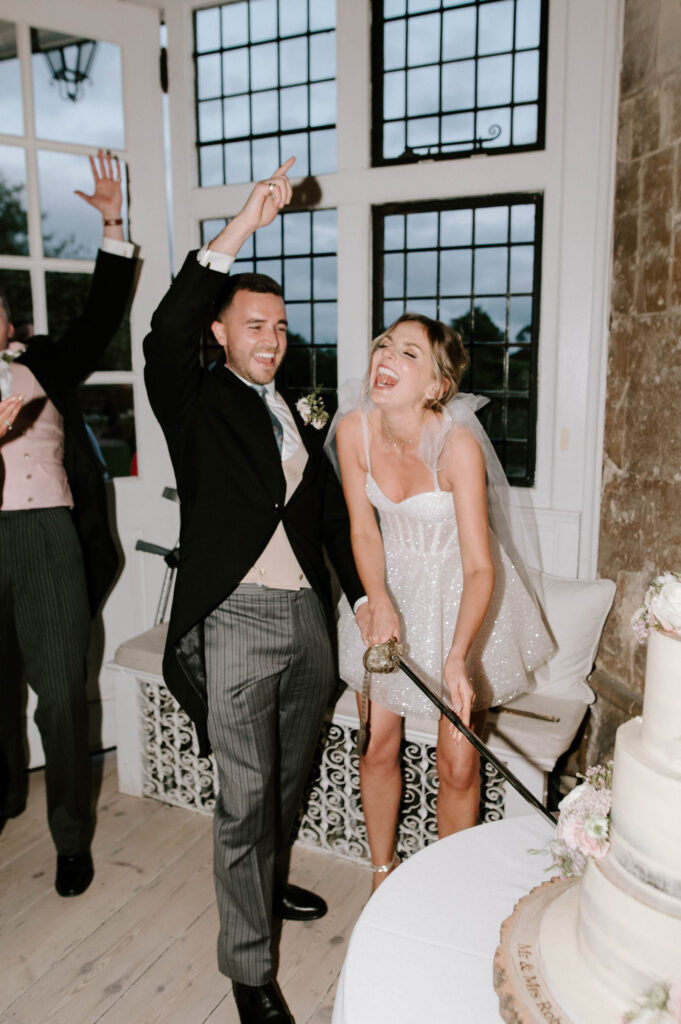 Bride and groom celebrating together with raised arms during the evening reception.