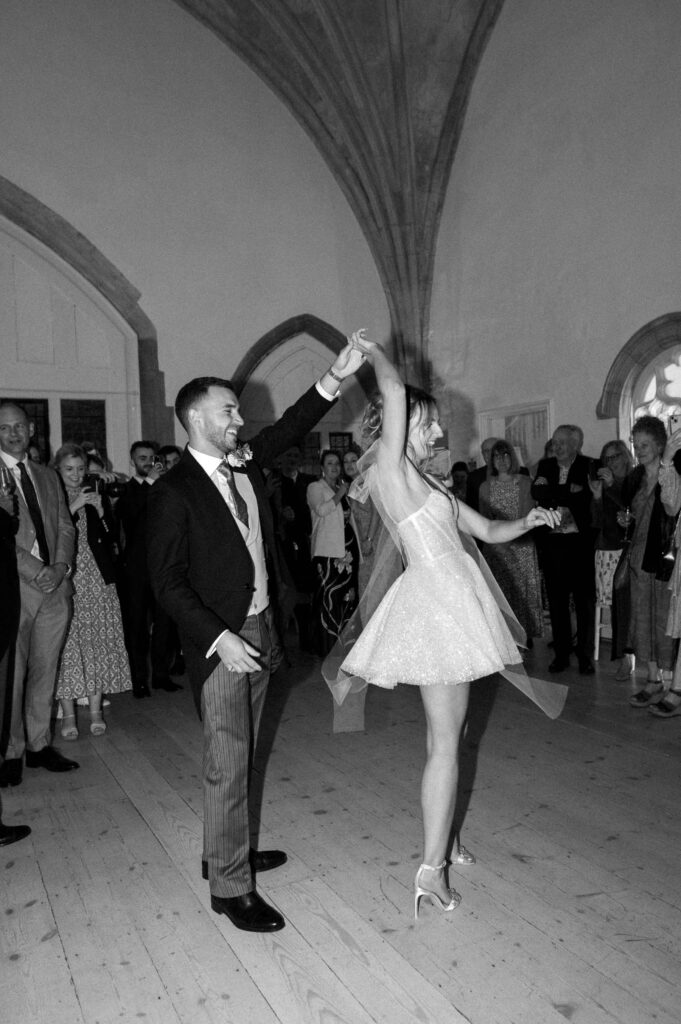Bride twirling as the groom watches during the wedding party.