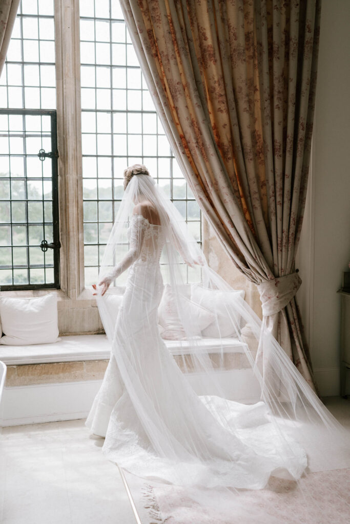 Bride walking gracefully in her wedding dress and veil inside the bridal suite at Butley Priory.
