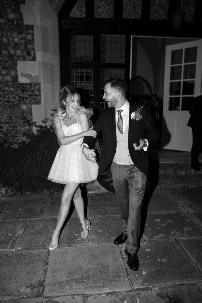 Bride and groom laughing together on the dance floor during the evening celebration.