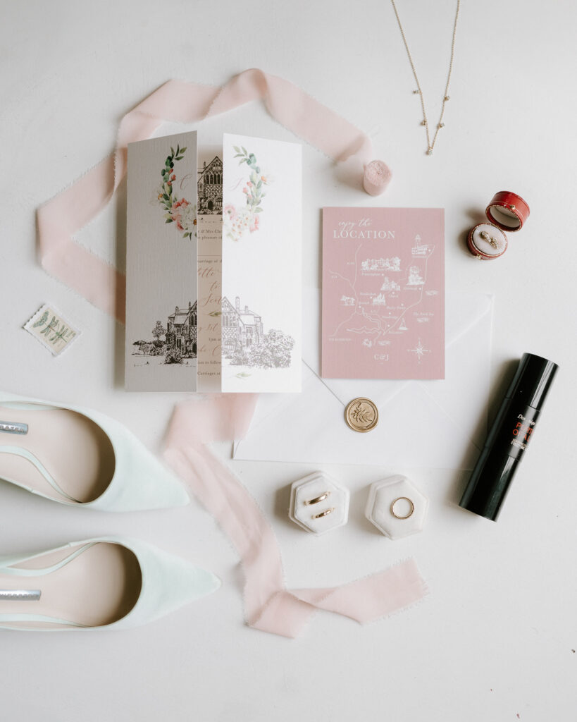 Flatlay of wedding morning details including perfume, jewellery and invitations at Butley Priory.