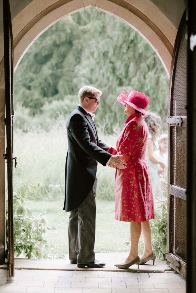 groom and mother of the bride having a moment at front of church before the ceremony