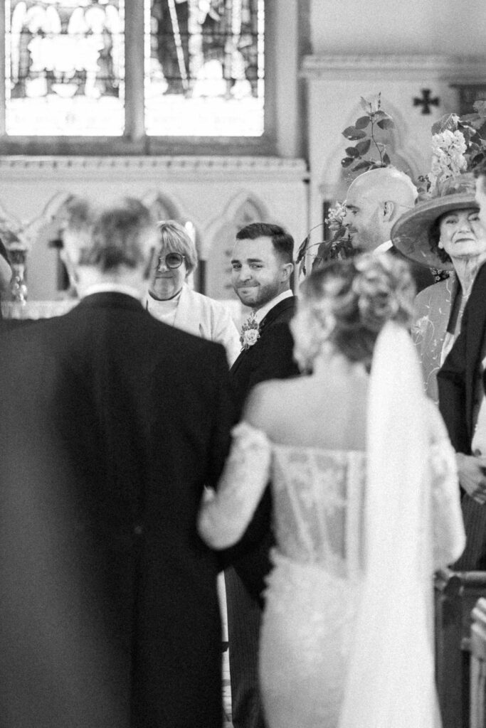 groom looking at his bride walking down the aisle and getting emotional