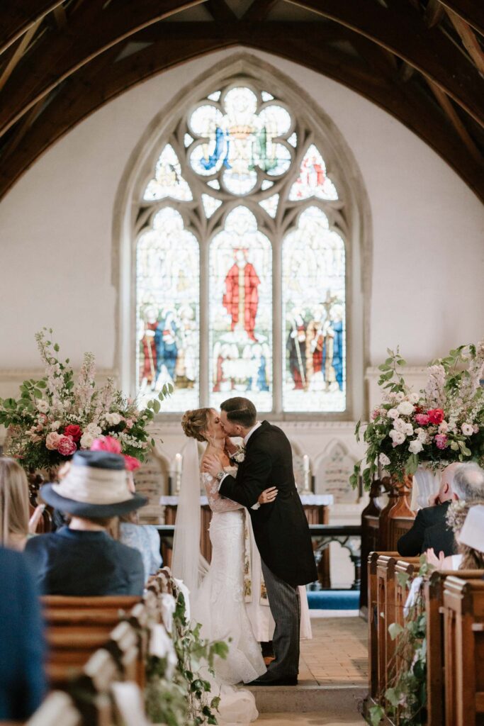 bride and groom sharing first kiss at church after getting married
