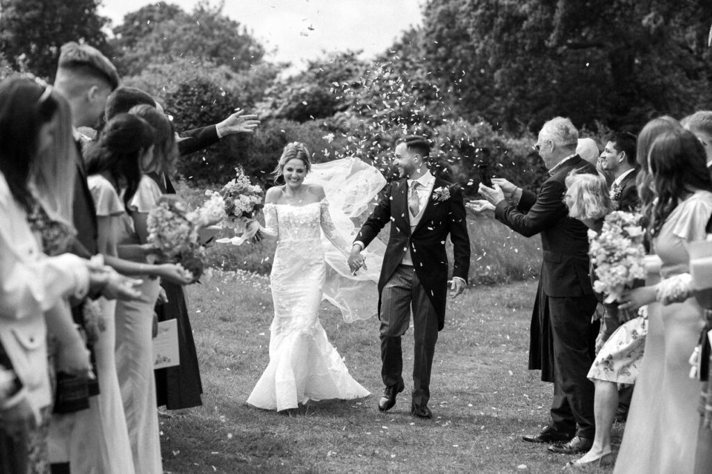 Bride and groom walking together through confetti moments after their wedding ceremony.