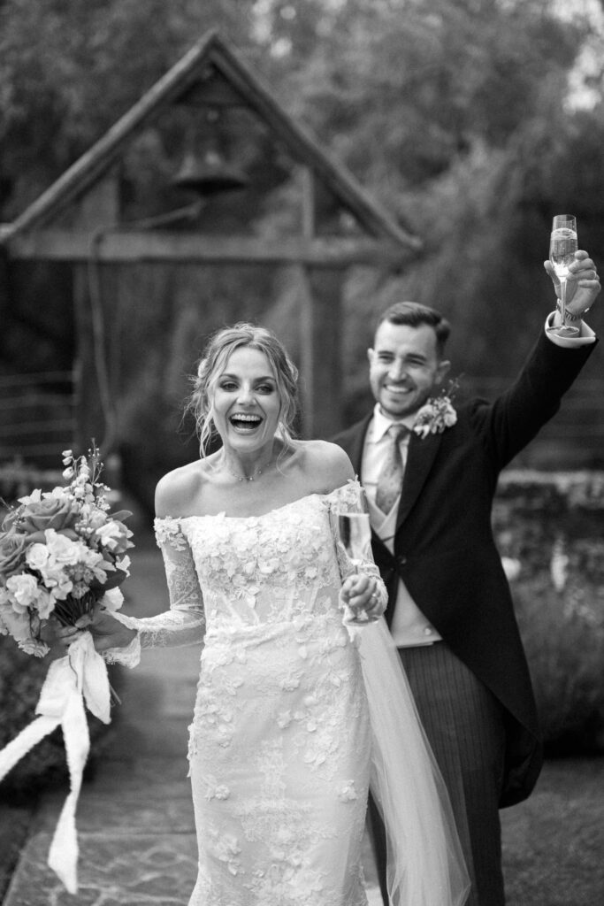 Bride and groom celebrating together after the ceremony, smiling and raising their hands.