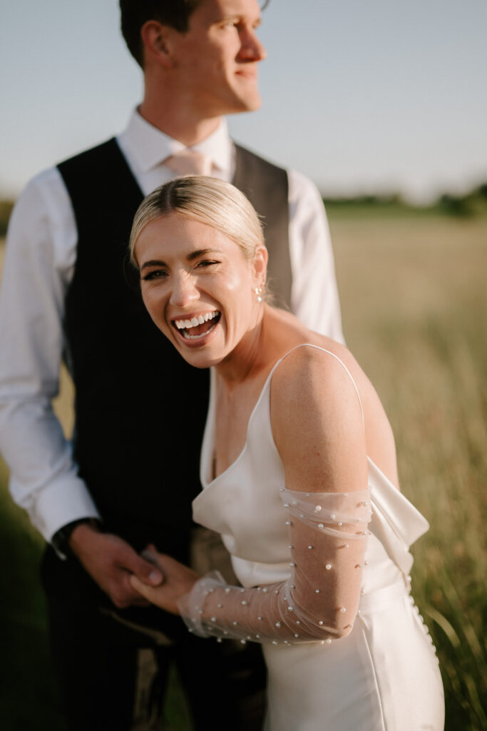 Bride laughing during golden hour portraits in a Suffolk field