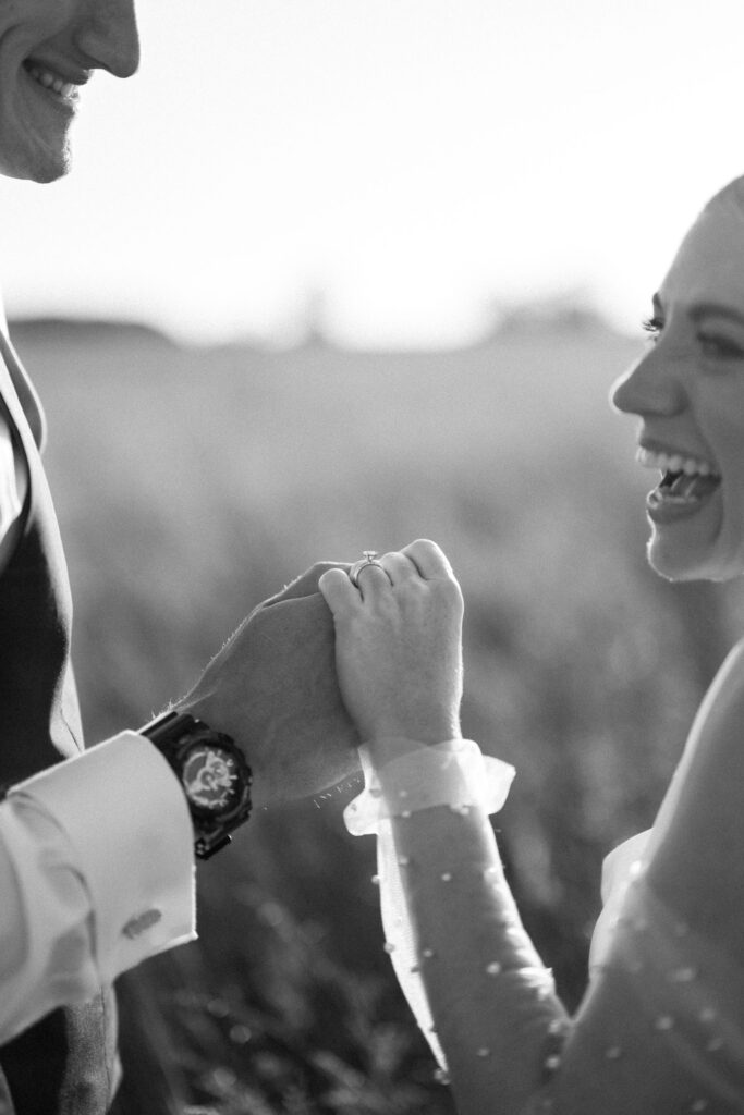 Close up of bride and groom holding hands during golden hour