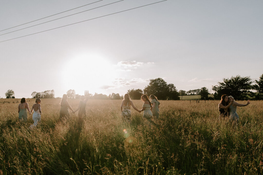 bridesmaids walking off in field into sunset
