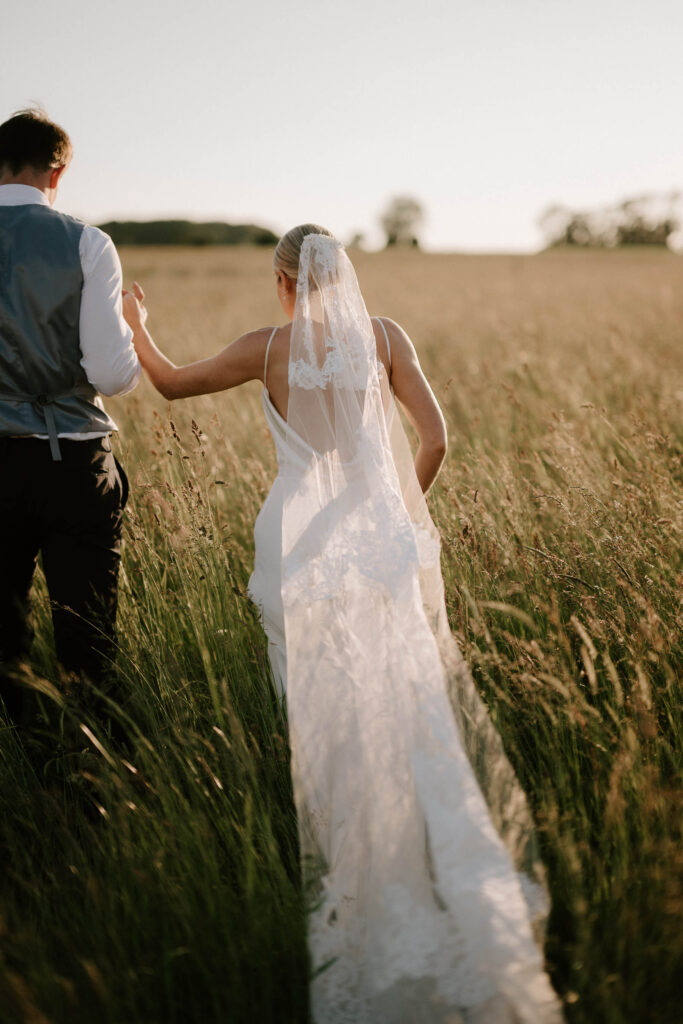 Bride walking through long grass during golden hour portraits