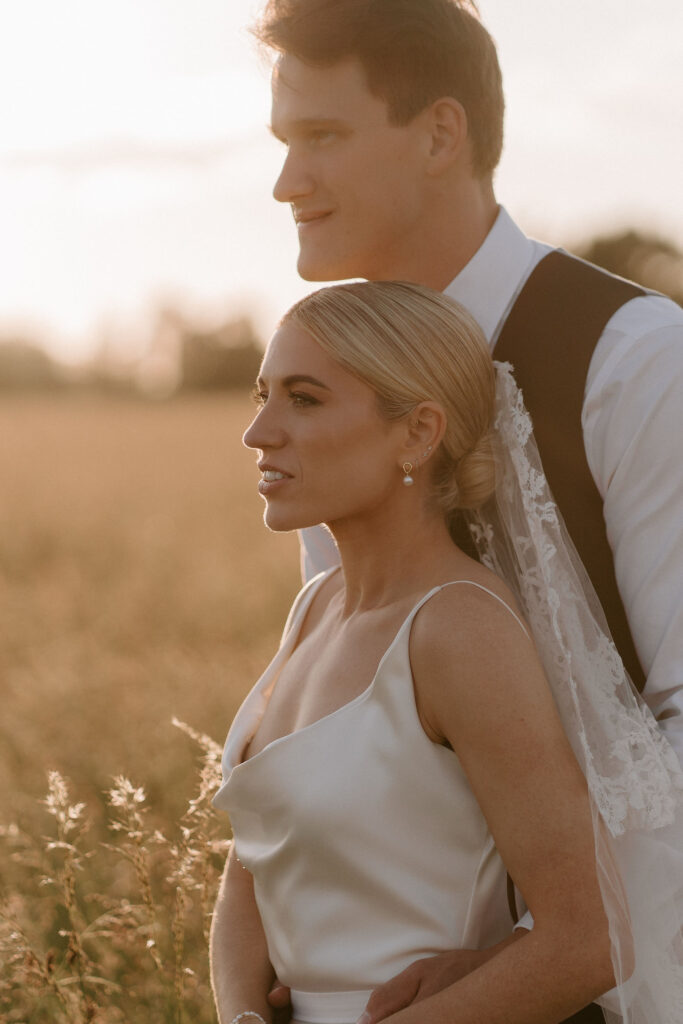 Bride looking out over a field during golden hour portraits