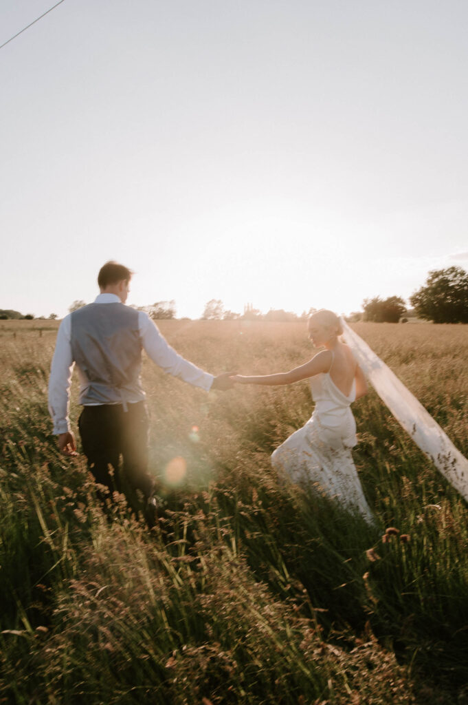 Bride and groom holding hands during countryside portraits in Suffolk