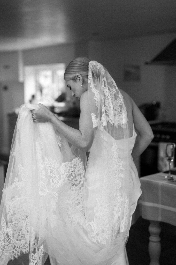 bride holding veil with lace detail walking away