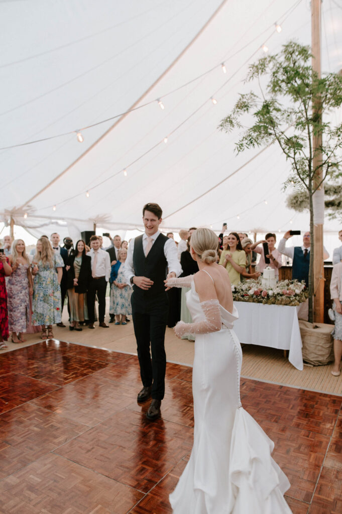 Bride and groom dancing together under marquee