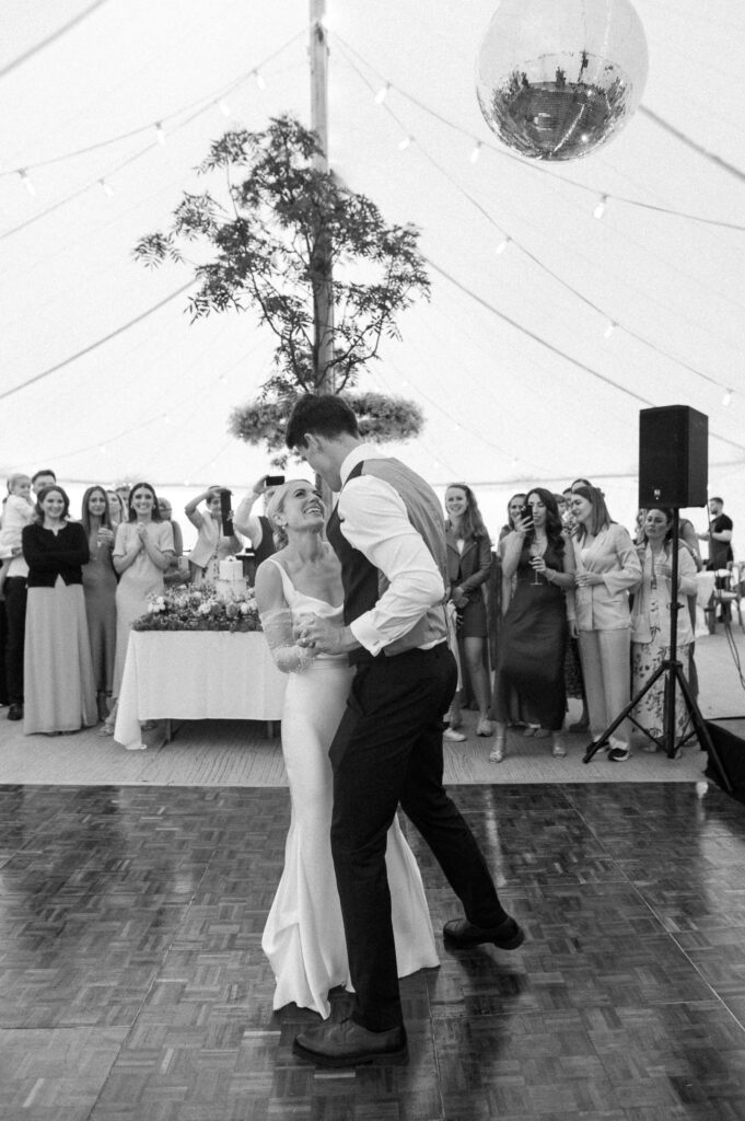 Bride and groom dancing surrounded by guests at marquee wedding reception in Suffolk