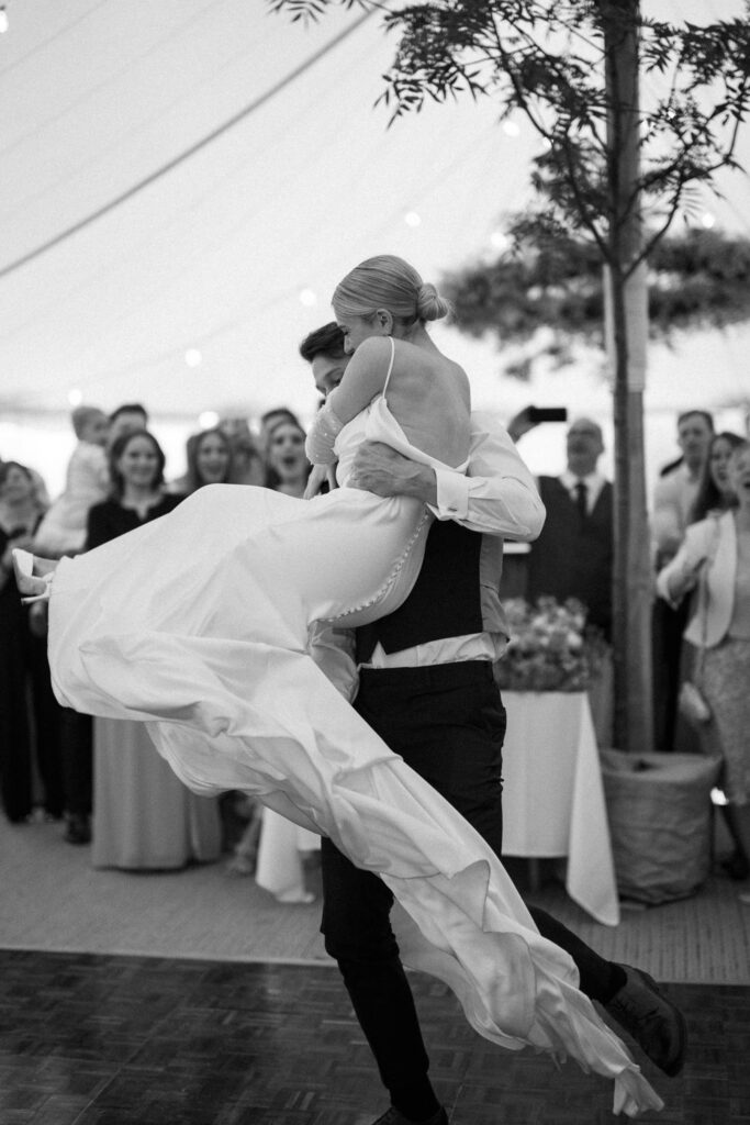 Groom lifting bride during first dance under marquee at Suffolk wedding