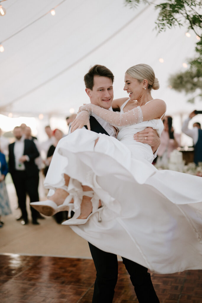 Groom lifting bride during first dance under marquee at Suffolk wedding