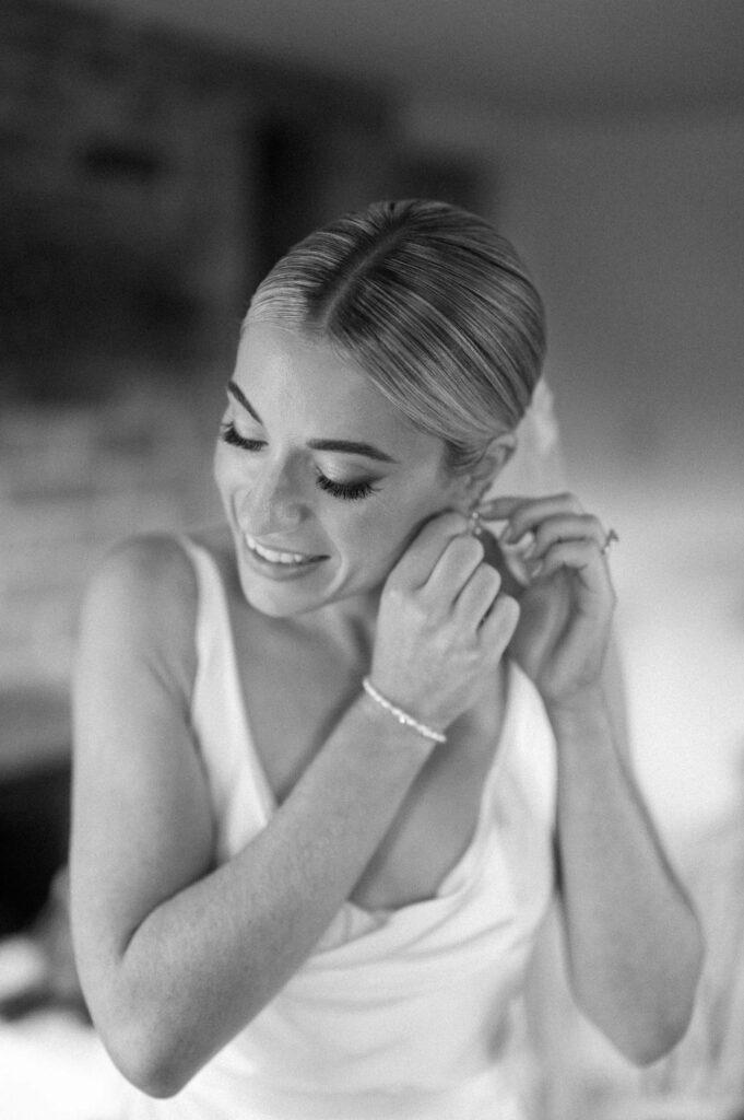 bride putting on earrings on wedding morning