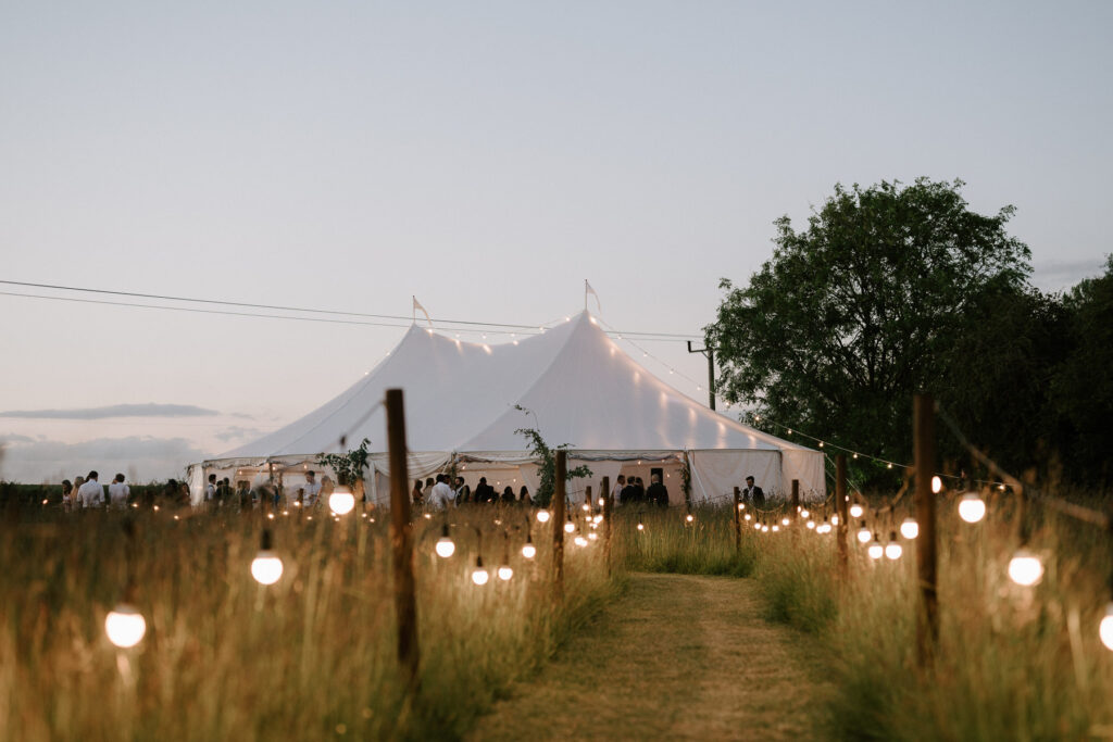 Outdoor marquee wedding reception on private land in Suffolk with festoon lights
