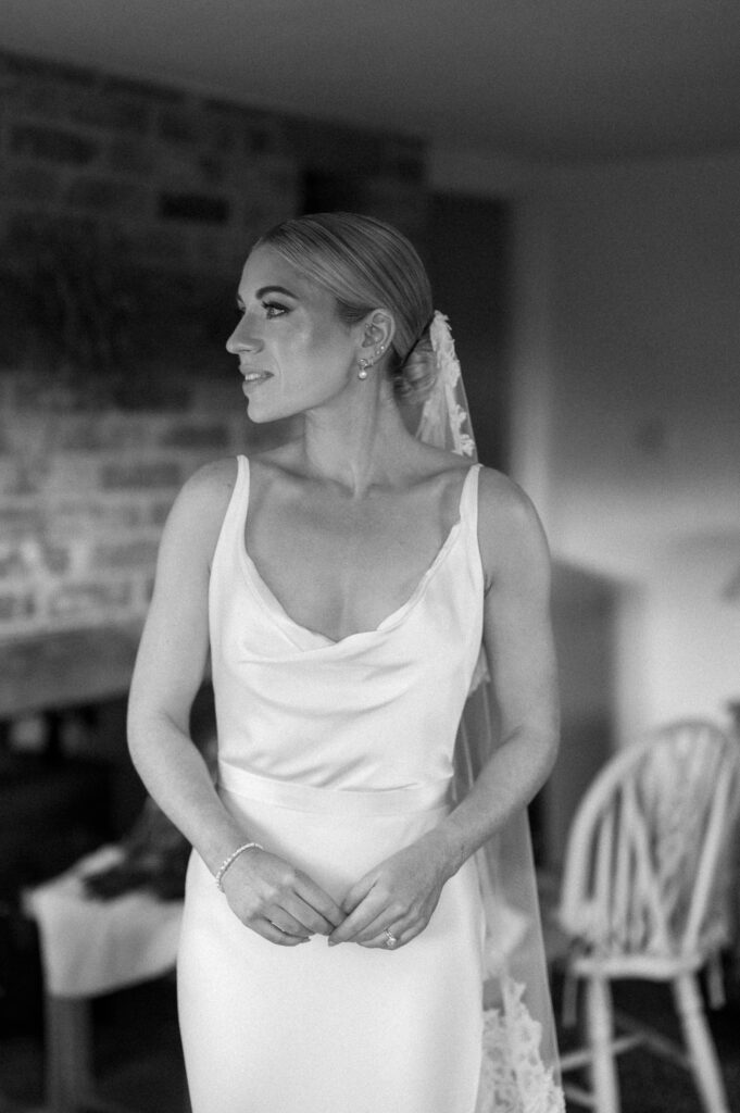 Bridal portrait of bride in satin wedding dress and low bun updo at Suffolk wedding venue