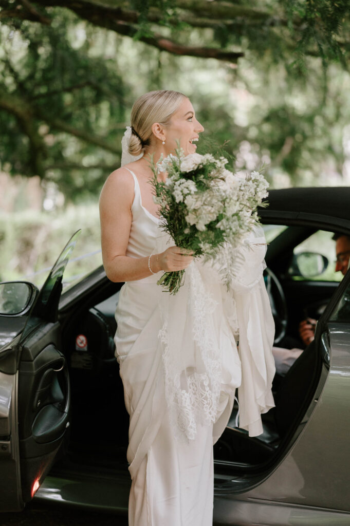 Bride stepping out of the car holding her bouquet before the ceremony