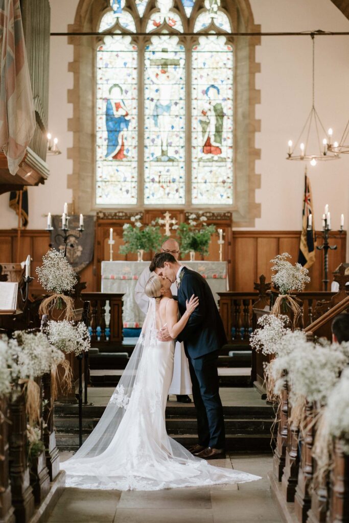 Bride and groom kissing at the altar after their vows
