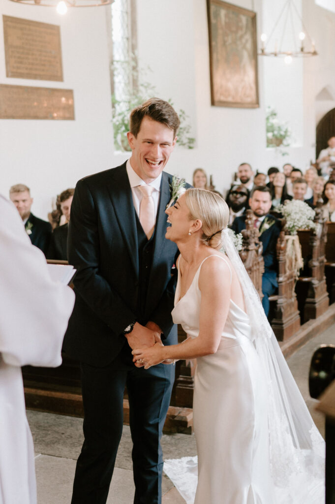 Bride and groom smiling and laughing as they walk down the aisle