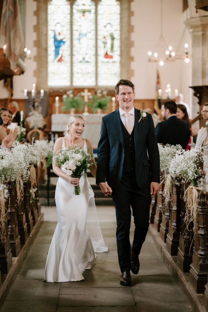 Bride and groom walking down the aisle inside the church after the ceremony