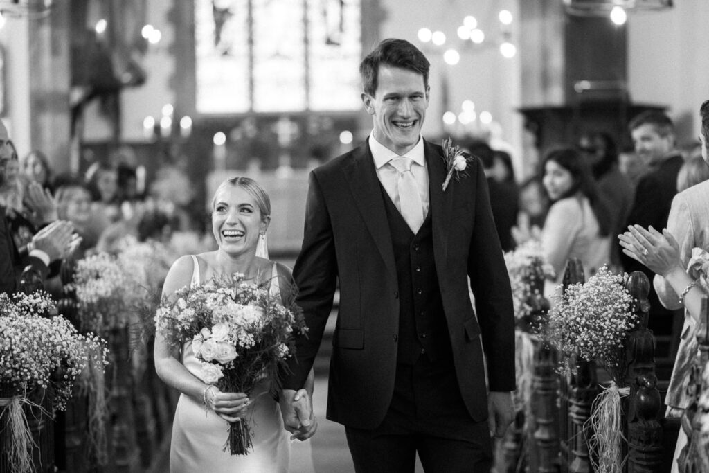 Bride and groom walking through confetti outside the church