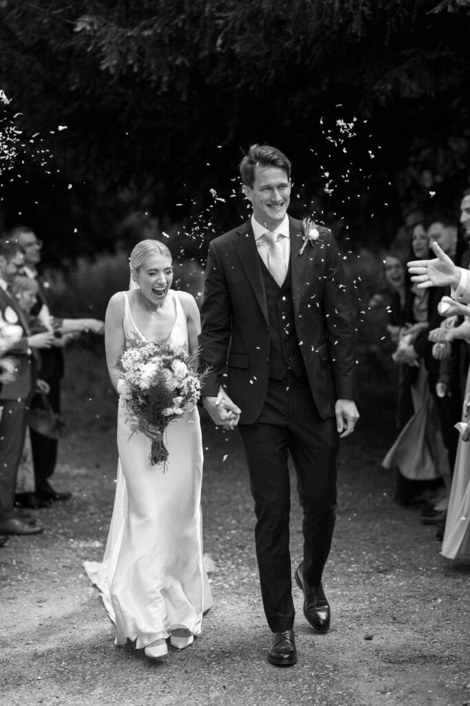 Bride and groom laughing as confetti is thrown during the church exit
