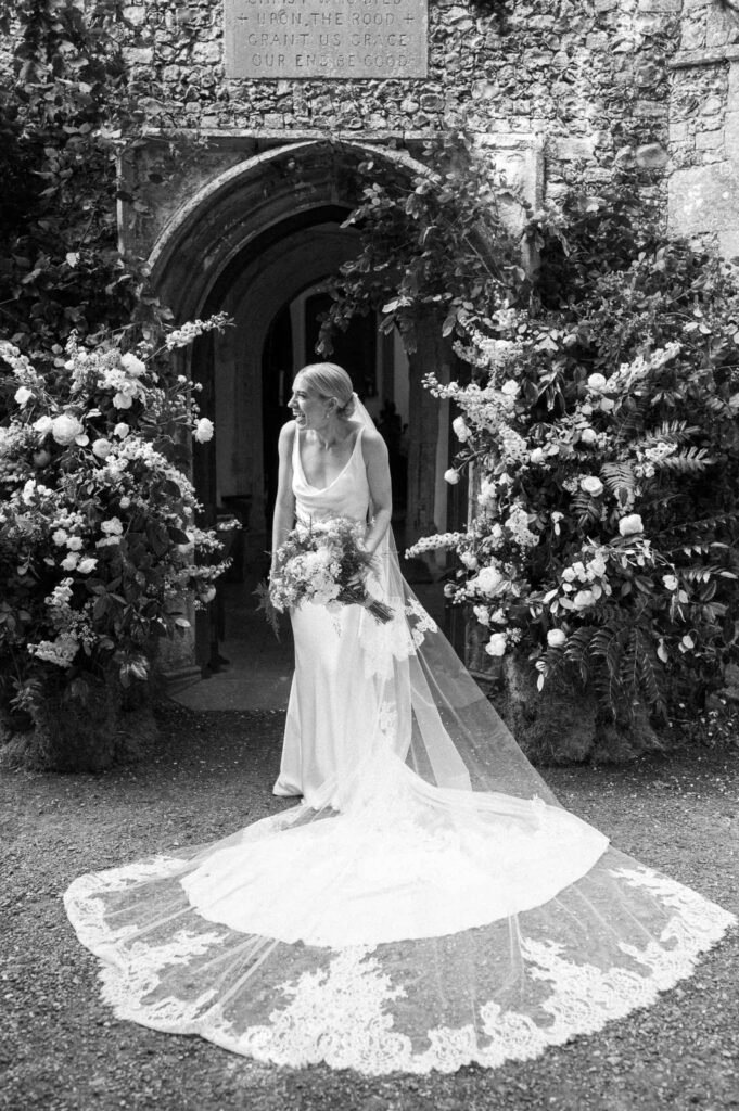 Bride standing outside the church doors in Earl Soham holding her bouquet on her wedding day