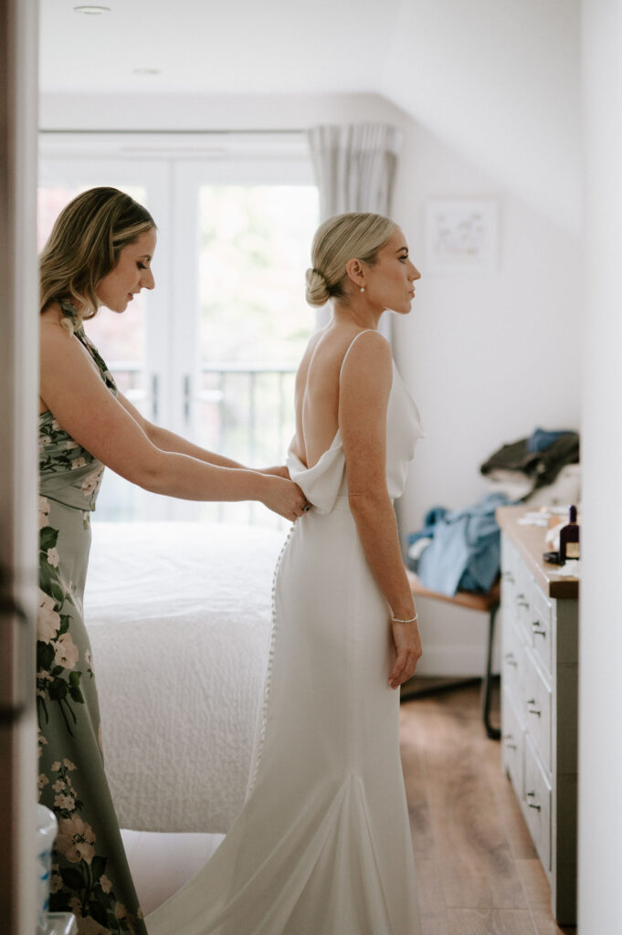 Bride getting into wedding dress on wedding morning