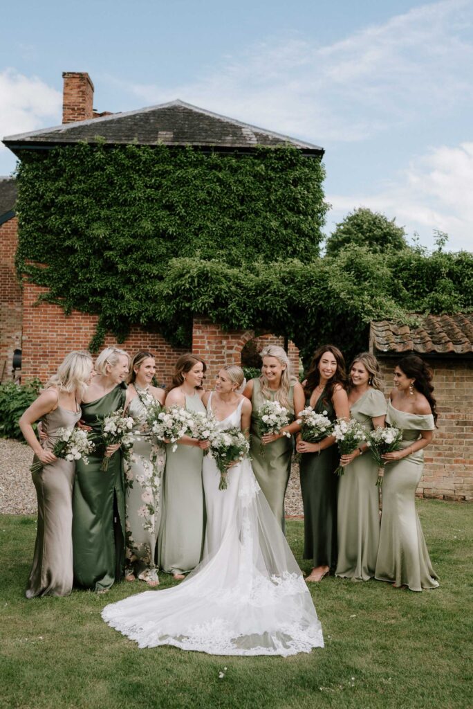 Bridesmaids standing together holding bouquets outside the church in Suffolk