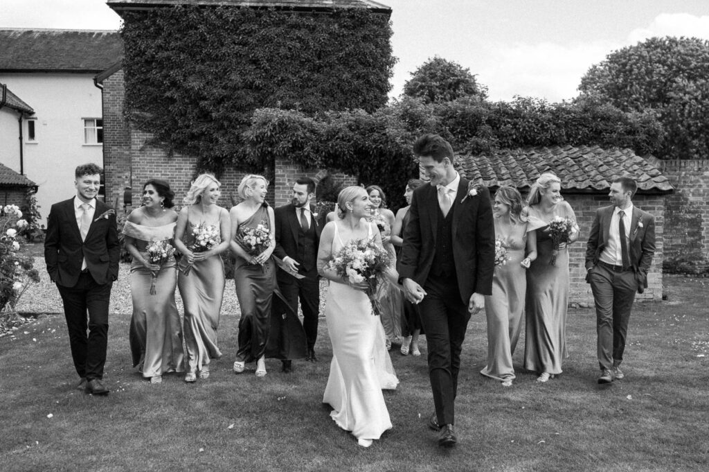 Bride and groom walking together with their wedding party behind them on the grounds