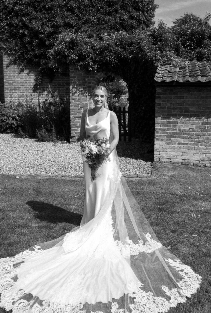 Bride standing alone holding her bouquet in the sunshine after the ceremony