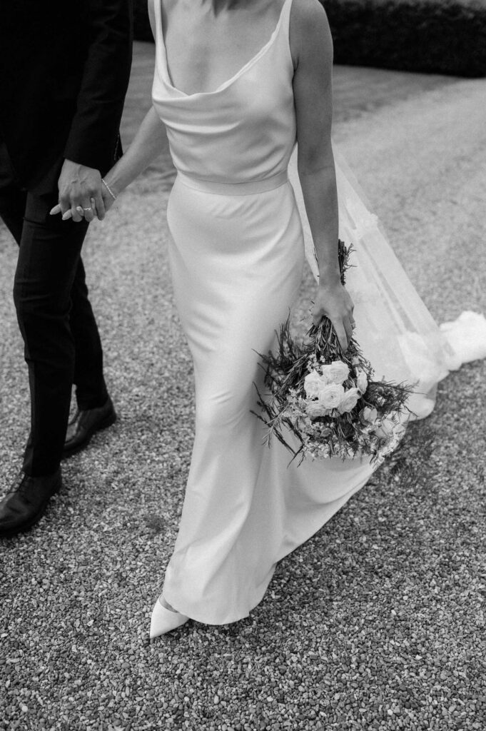 Close up of the bride’s dress and bouquet while walking with the groom