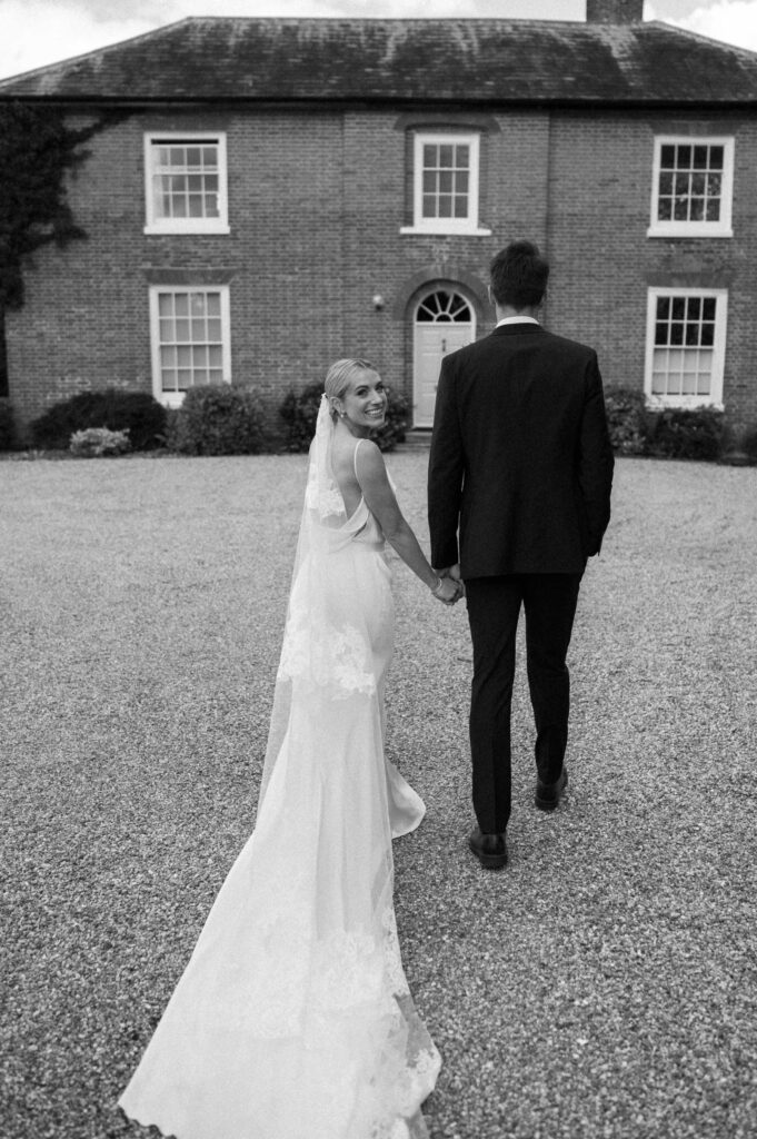 Bride and groom holding hands walking across the grounds after their church wedding