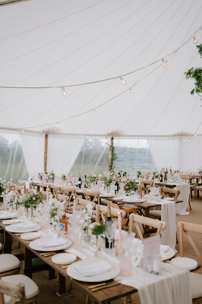 Marquee wedding reception set up with long tables and greenery