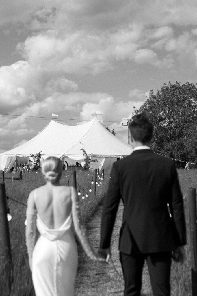 Bride and groom walking away together towards the reception marquee