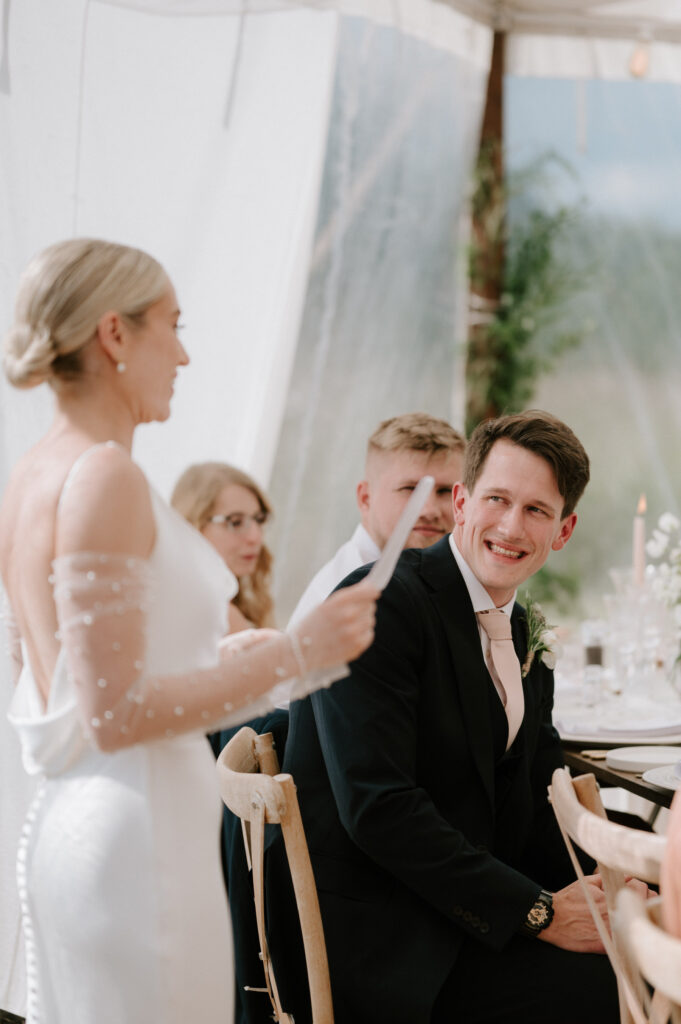 groom smiling at bride during wedding speech