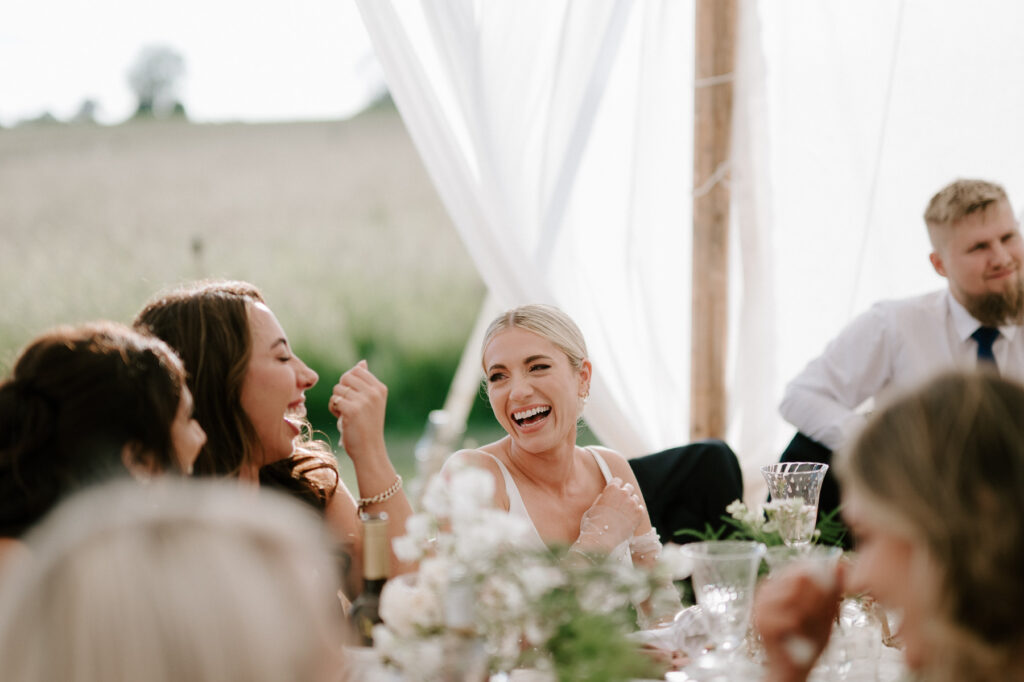  bride laughing during reception speeches