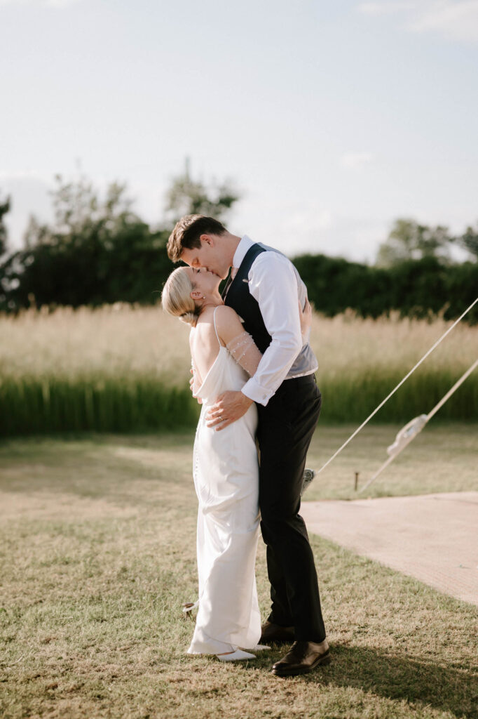bride and groom kissing at golden hour outside marquee wedding venue in suffolk